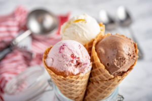 Tres helados de cono de tres sabores diferentes: chocolate, vainilla y fresa.